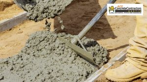 Concrete contractor using a tool to spread out concrete mix