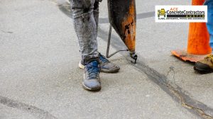 person pouring asphalt on concrete