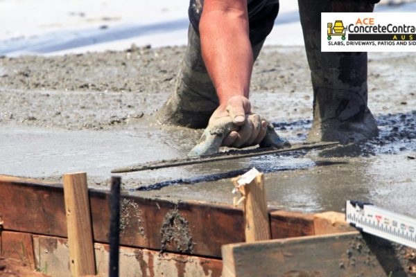 person smoothening wet concrete using trowel
