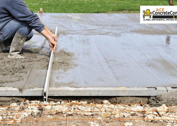 A concrete contractor is using a tool to flatten wet concrete