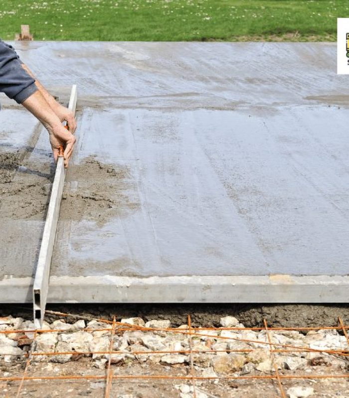 A concrete contractor is using a tool to flatten wet concrete